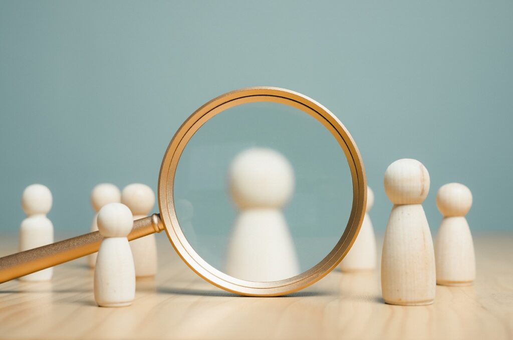 A magnifying glass looking at game pieces show how this article will look at the details between Solarwinds database software alternatives.