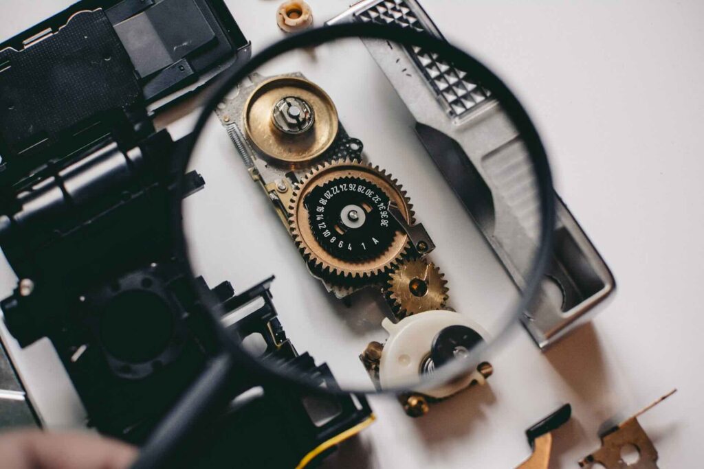 A magnifying glass looking at a small gear visualizes database observability.